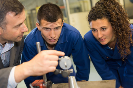 male engineer itaking precision measurement with apprentices