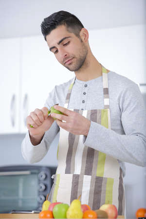 man cuts fruits in the kitchenの写真素材