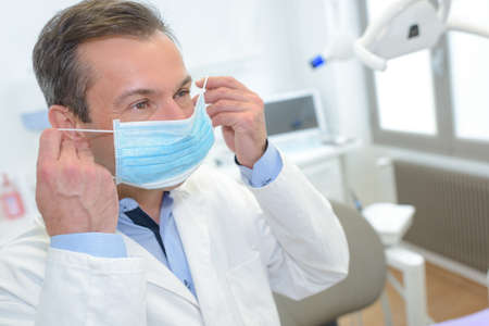 male dentist putting on maskの写真素材