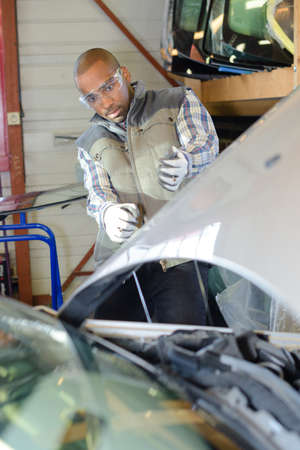 mechanic leaning back to look a car engineの写真素材