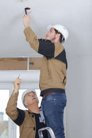 workman making hole in ceiling for lightの写真素材