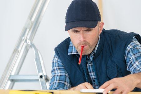 Tradesman working with pencil in his mouth