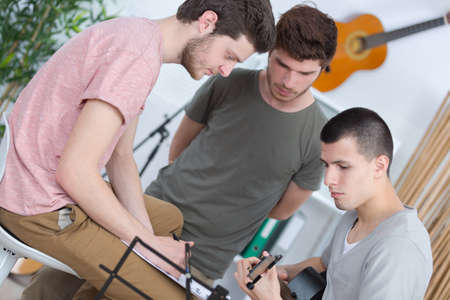 happy friends playing guitar and listening to music at homeの写真素材