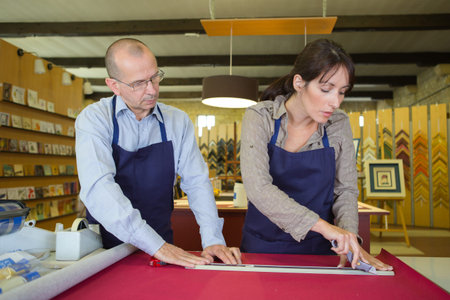happy sellers working with picture frames in atelier