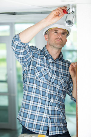 technician adjusting cctv camera on wallの写真素材
