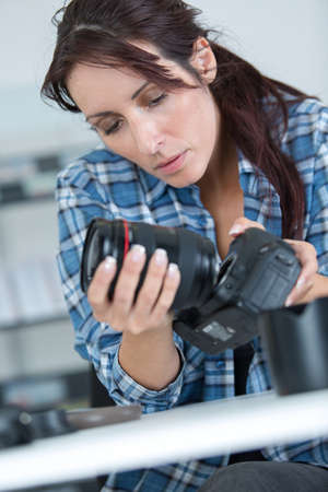 female photographer holding a professional camera - isolated over whiteの写真素材
