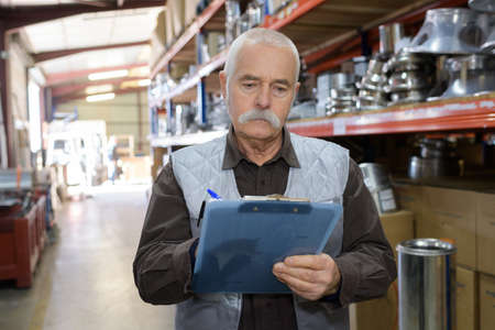 worker with white helmet and clipboard in warehouseの写真素材