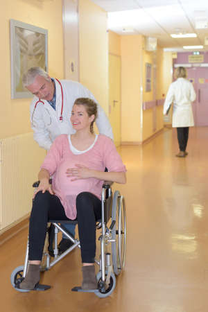 pregnant woman being pushed on the wheelchairの写真素材