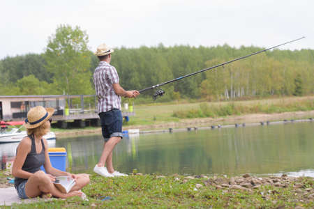 young couple fishing on the banks of the pondの写真素材