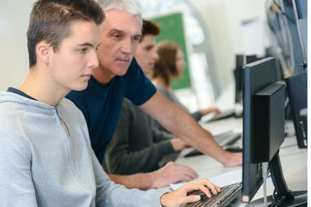 teacher helping an it student with her workの写真素材