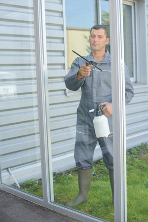 man cleaning windows with squeegee