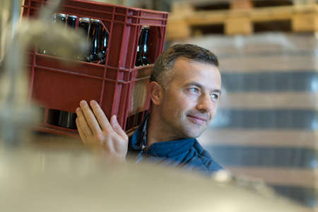beer manufacturer carrying pack of beer bottles in breweryの写真素材