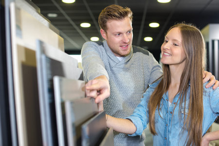 young happy couple looking at bathroom tile in furniture storeの写真素材