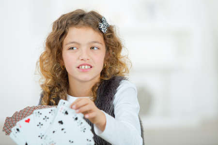 portrait of smiling little girl playing cardsの写真素材