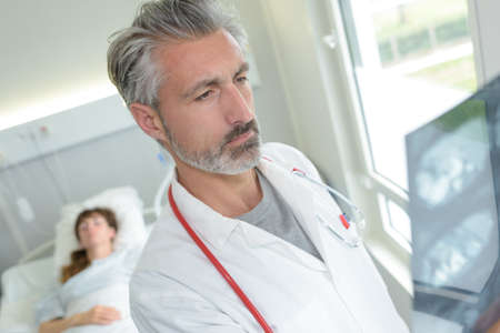 doctor examining x-rays in patients roomの写真素材