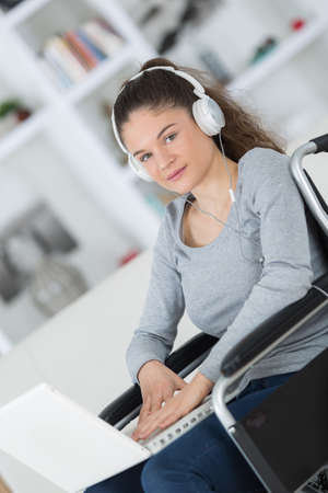 young woman on the wheelchair with headset onの写真素材
