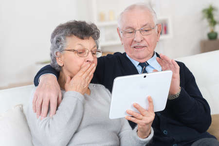 mature couple using a digital tablet in their apartmentの写真素材