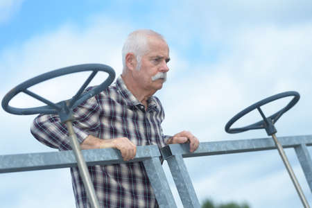 senior worker next to big valves in an industrial plantの写真素材