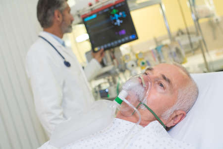 doctor examining his patient wearing oxygen maskの写真素材