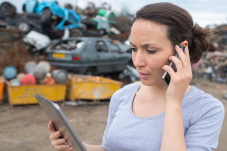 woman with mobile phone and file folder outside factory