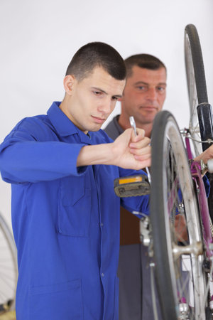 young man repairing bicycle with spanner