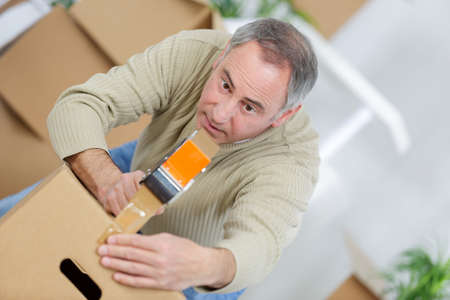 man packing a moving box using an adhesive tapeの写真素材