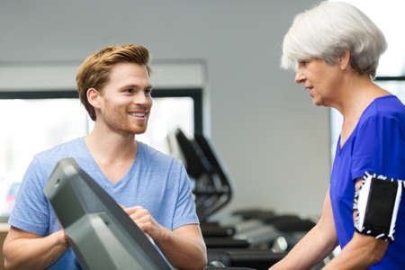 aged woman exercising with fitness instructor in the gymの写真素材
