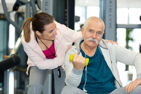 happy senior working-out with weights and personal fitness trainer