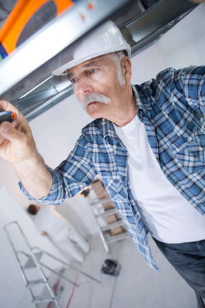 man making mount for electrical wires on ceilingの写真素材