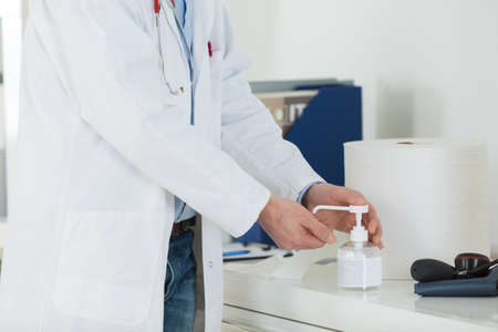 medical doctor using sanitizer dispenser in clinicの写真素材