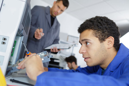 young technician sitting near copier