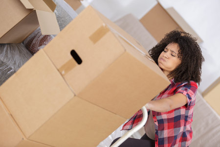 exhausted woman pushing trolley full of boxes