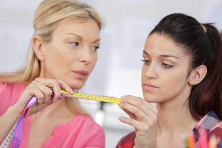 ressmaker gets shoulders measures of client in the showroomの写真素材