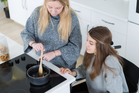 disabled woman in wheelchair preparing meal with friend in kitchen