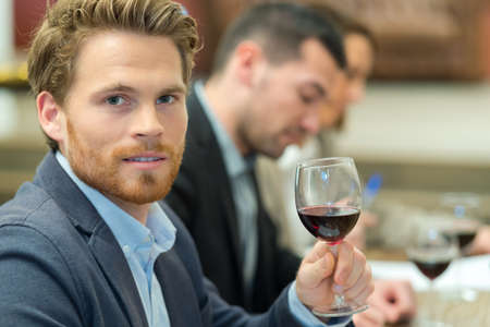 handsome businessman holding a wine glass in restaurantの写真素材