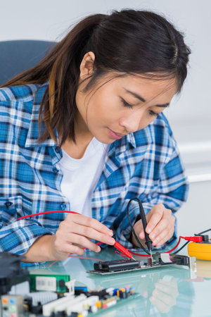 woman with a tester and a printed circuit board
