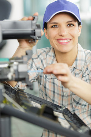 happy woman fixing a photocopier during maintenance