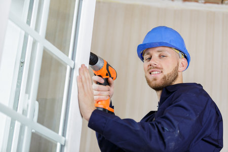 male tradesman using drill on pvc wnidow