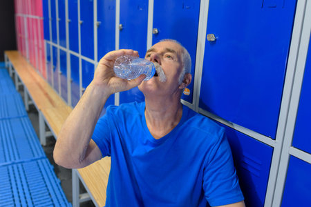man drinking water in locker-room