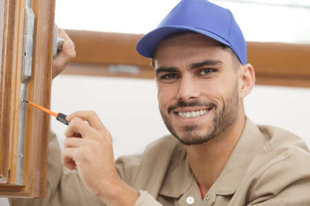 young man contractor screwing window handle mechanismの写真素材
