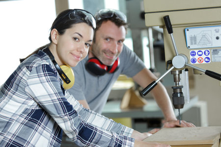 young woman as apprentice in wood construction learns with luthier