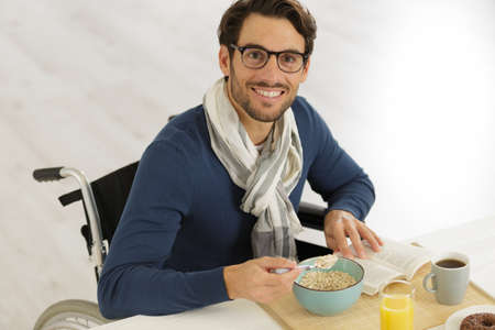 positive disabled man having cereal in the living roomの写真素材