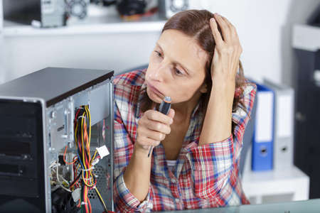 confused woman fixes pc component in service centerの写真素材