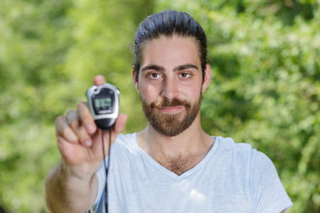 portrait of young man holding a digital stopwatchの写真素材