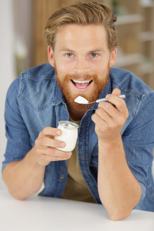 young man eating natural yoghurt