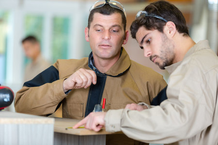 young factory carpenter measuring a plank