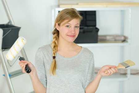 beautiful woman has the choice between paint roller and brushes