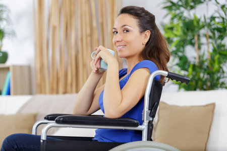 disabled woman in wheelchair drinks a coffee at home