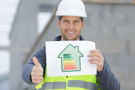 happy builder pointing finger and holding clipboard sales chartの写真素材