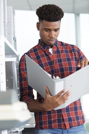 young businessman taking folder from shelf at workplace